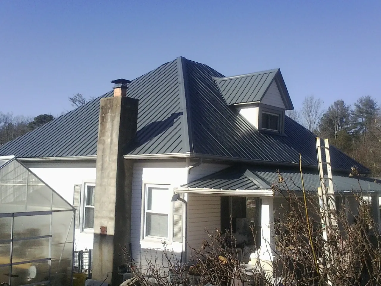 Dark blue standing seam metal roof on a white farmhouse with dormer — Slate & Tile Roof Repair by Roofing Brothers in Mauldin