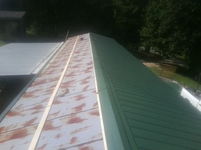 Old rusted panels beside newly installed green metal roofing — Wind Damage Roof Repair by Roofing Brothers in Mauldin