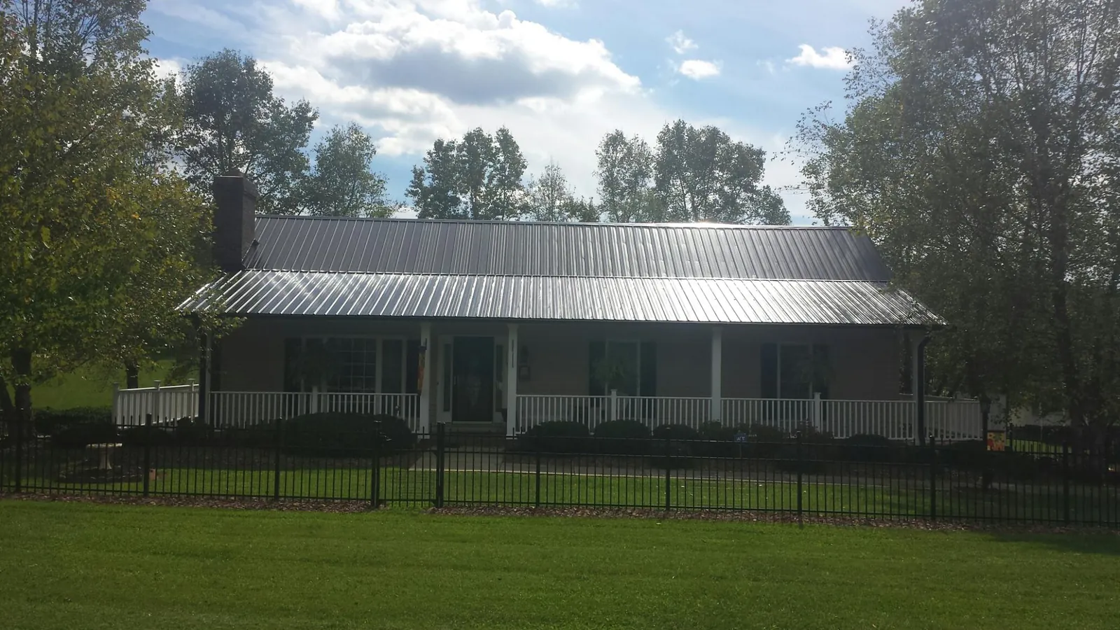 Gray metal roof on a brick ranch with a full width front porch — Gutter Guard Installation work by our crew in Mauldin
