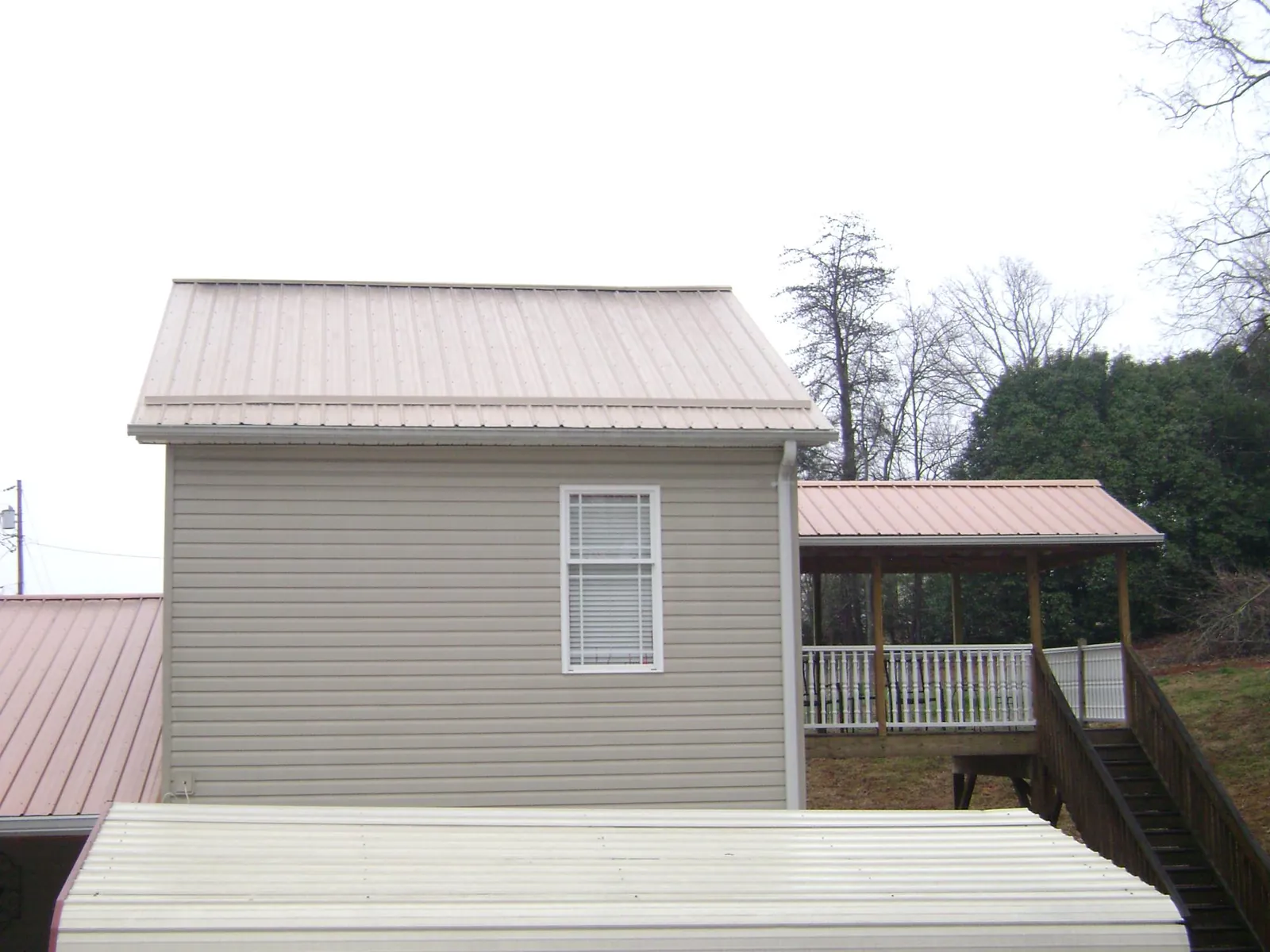 Tan metal roofs on a two story addition and attached porch, from a Roof Replacement job in Mauldin