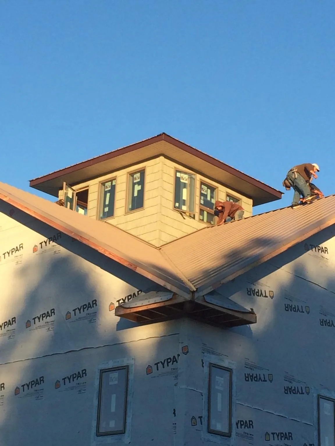 Roofers working around a rooftop cupola on a new metal roof at sunset — Roof Waterproofing in Mauldin by Roofing Brothers